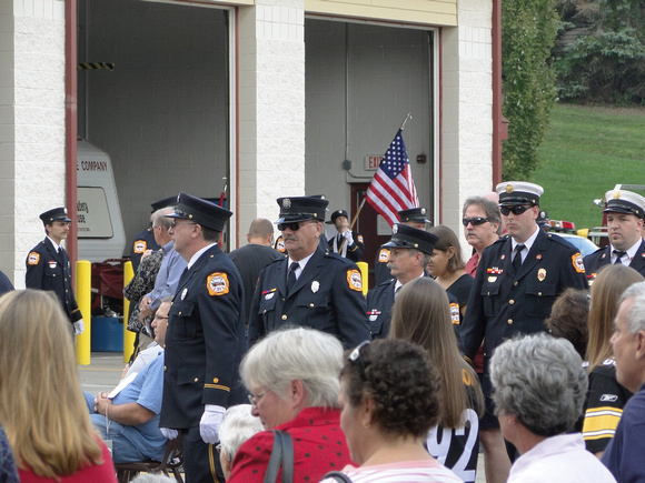 Firemen in their dress uniforms form a procession toward the stage area